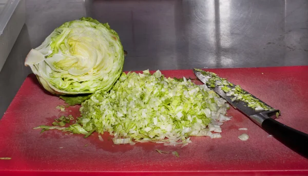 Fresh Iceberg salad on red carving board.