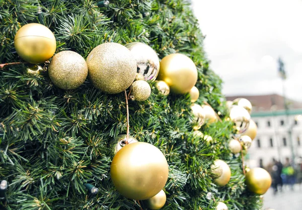 close up photography of a decorated outdoor Christmas Tree. With buildings blurred out in the background.