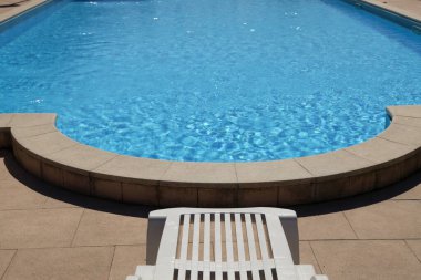 Havuzun yanındaki beyaz plastik iskemle.