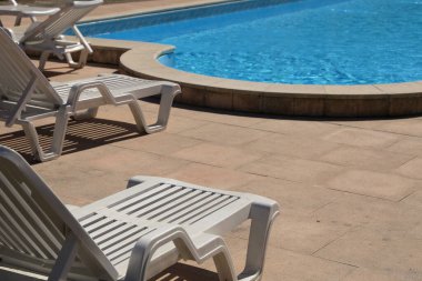 Havuzun yanındaki beyaz plastik iskemle.