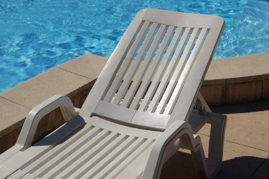 Havuzun yanındaki beyaz plastik iskemle.