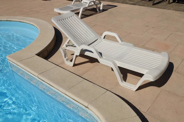 white plastic deck chair by the pool