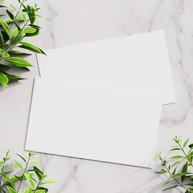 Yeşil yapraklarla çevrili mermer bir yüzeye yerleştirilmiş boş bir beyaz kart, modeller ve minimalist tasarımlar için ideal..