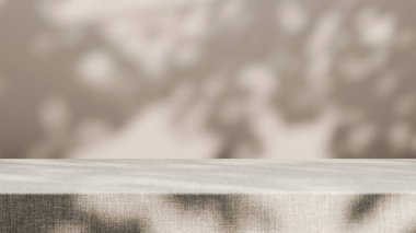 Yumuşak bej arka planda bulanık yaprak gölgeleri olan desenli kumaş masa yüzeyi. Minimum ve doğal bileşim, ürün modellemeleri, kozmetik gösterimler, organik markalaşma ve yaşam tarzı tasarım projeleri için mükemmel..