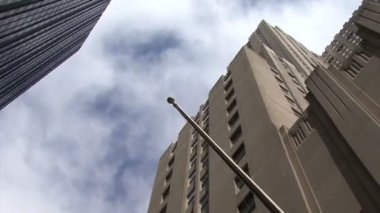 Bulutlu gökyüzü ve gökdelenler ile New York sokaklarından düşük açılı bir görünüm.