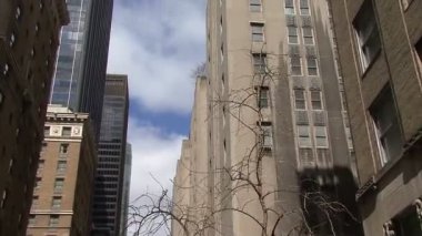 Bulutlu gökyüzü ve gökdelenler ile New York sokaklarından düşük açılı bir görünüm.
