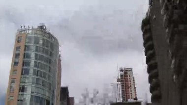Bulutlu gökyüzü ve gökdelenler ile New York sokaklarından düşük açılı bir görünüm.
