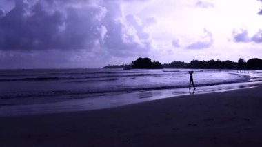 Akşam Hint okyanusu, ıssız bir plaj, uzakta yalnız bir adam suya gider