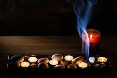 Koyu arka planda sigara aroma konisi ile taşlı mumspa tepsi