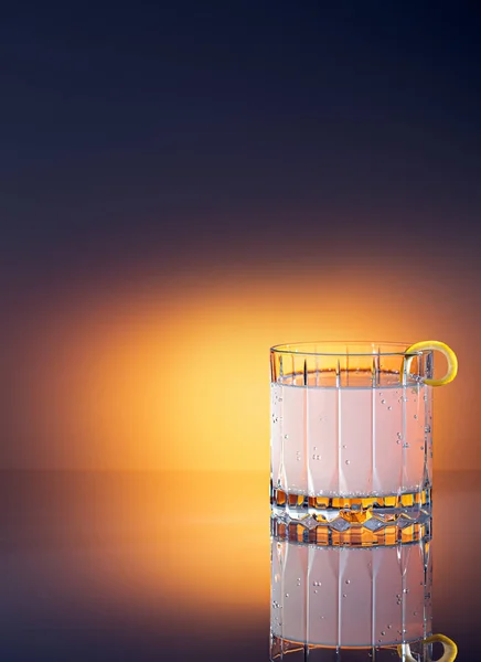 Crystal glass of tonic water with lemon with colourful gradient background