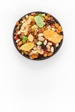 Beyaz arka planda, yuvarlak kasede kurutulmuş karışık meyve ve fındık.