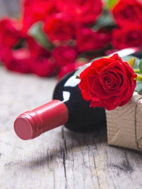 Bir şişe kırmızı şarap, tirbuşon, hediye, rustik eski antika arka plan üzerinde kırmızı gül buketi. Bir tatil için yıldönümü, Sevgililer günü kutlama ayarla