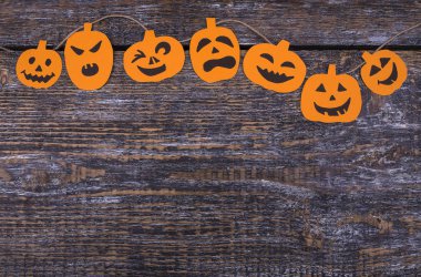 Kağıt hancraft turuncu yaratıcı desenle korkunç kabaklar, metin altında yer ahşap bir zemin üzerine bir ip üzerinde teslim gülmek. Üstten görünüm.