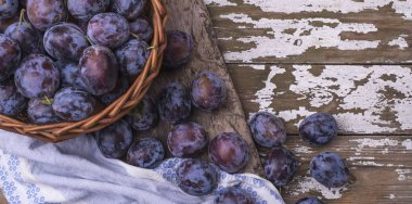 Büyük sepet altında metin Olgun doğal Erik - hasat meyve ahşap bir zemin üzerine yerleştirin. Vejetaryen doğal yeme. Üstten görünüm