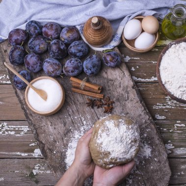 Ahşap bir masa üzerinde ev yapımı pasta pişirme için malzemeler. Erik kadın elinde yerden için taze aromatik hamur. Üstten görünüm.