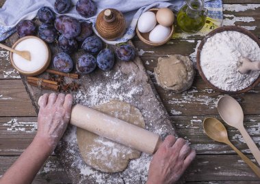 Taze malzemeler ahşap bir masa üzerinde ev yapımı pasta pişirme için. Aromatik hamur pasta Erik kadın elinde gelen için. Üstten görünüm.