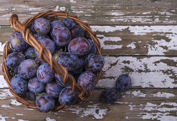 Büyük sepet altında metin Olgun doğal Erik - hasat meyve ahşap bir zemin üzerine yerleştirin. Üstten görünüm.