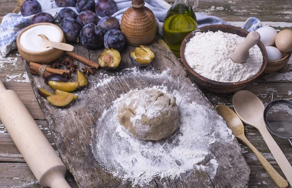 Ahşap bir masa üzerinde erik ile ev yapımı bisküvi pişirme için doğal organik maddeler. Taze aromatik hamur pasta grafiğinden bir gemide Erik için. Üstten görünüm.