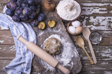 Pişirme işlemi elişi ev pasta Erik, hamur, yumurta ile metin altında ahşap bir arka plan üzerine yerleştirin. Üstten görünüm.