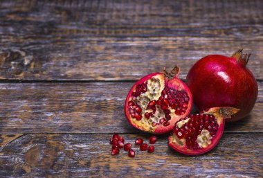 Olgun doğal meyve için taze meyve suyu - kırmızı nar meyve ahşap arka plan üzerinde bir parçası ile. Vegan kavramı.