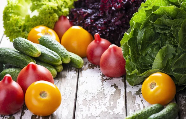 Свежесобранные натуральные органические овощи для здорового питания. Спелые помидоры, огурцы, зелень на деревянном фоне . — стоковое фото