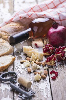 Ahşap bir masada şarap gül, peynir ve taze doğal nar seti.