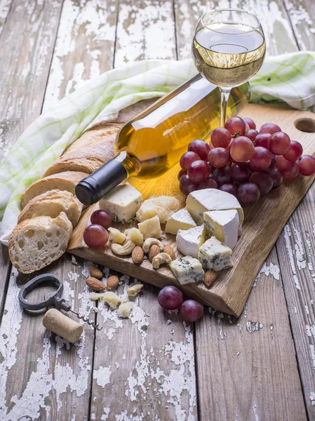 Deliciosas uvas, queso y vino blanco en una tabla de madera . —  Fotos de Stock