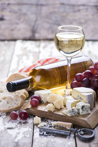 Botella de vino blanco y copa con queso y uvas sobre fondo de madera . —  Fotos de Stock