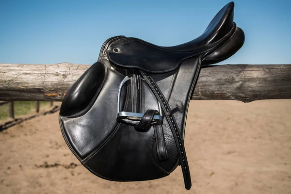 青い空の背景に木製の田舎のフェンスに馬の黒い革の鞍 コピースペース — ストック写真