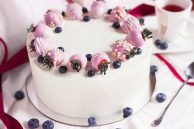 Beyaz bir arka plan üzerinde çikolata ve taze yaban mersini çilek ile Şenlikli beyaz kek. Yan görünüm