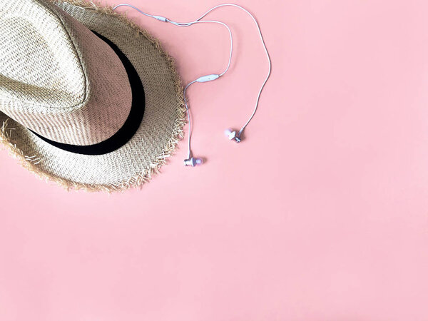 Woven hat and white ear phone on pastel pink color background su