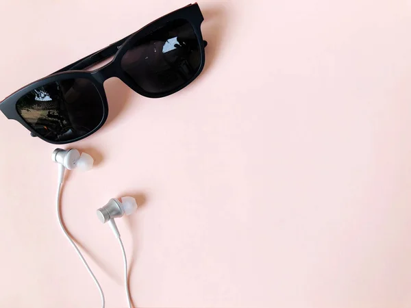 Ohrhörer und Sonnenbrille auf pastellrosa Hintergrund Sommer — Stockfoto
