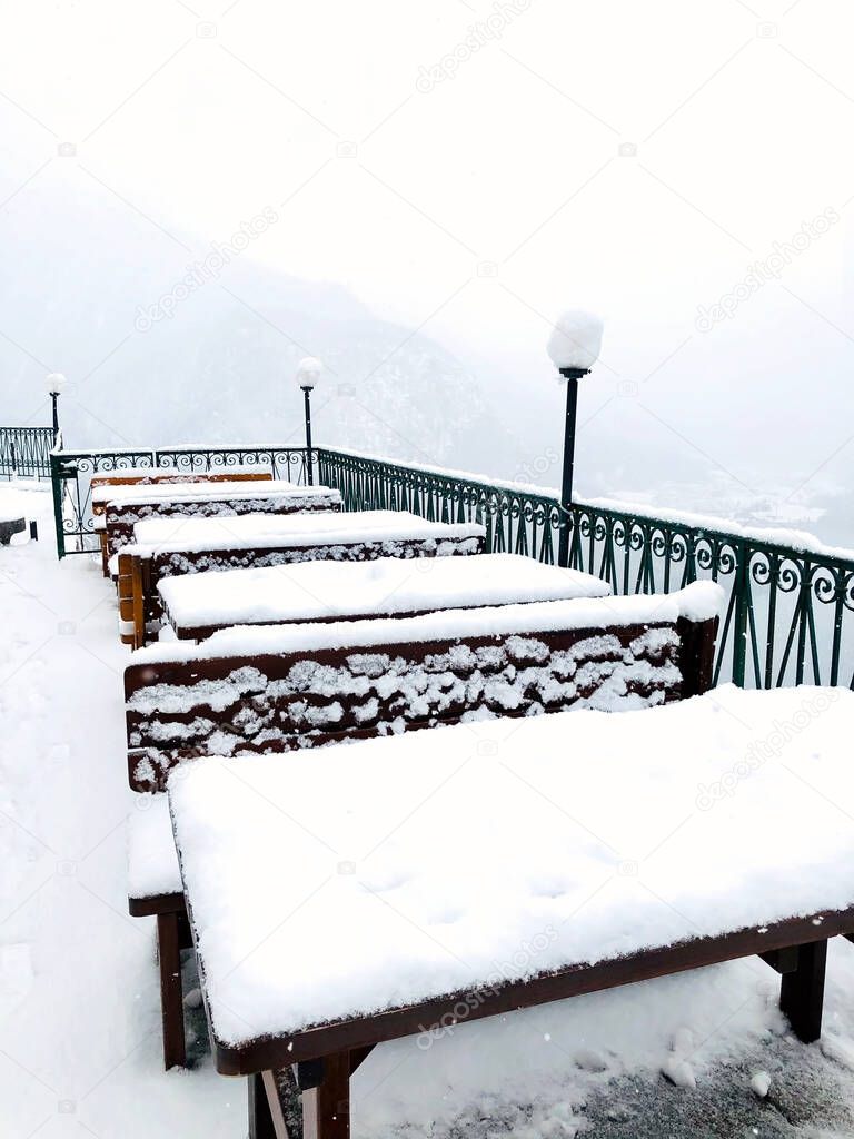 Closeup snow table outdoor restaurant at Hallstatt winter snow mountain landscape leads to the old salt mine of Hallstatt, Austria