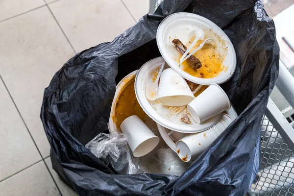 塑料垃圾袋中的环境不友好发泡胶板和杯子 — 图库照片