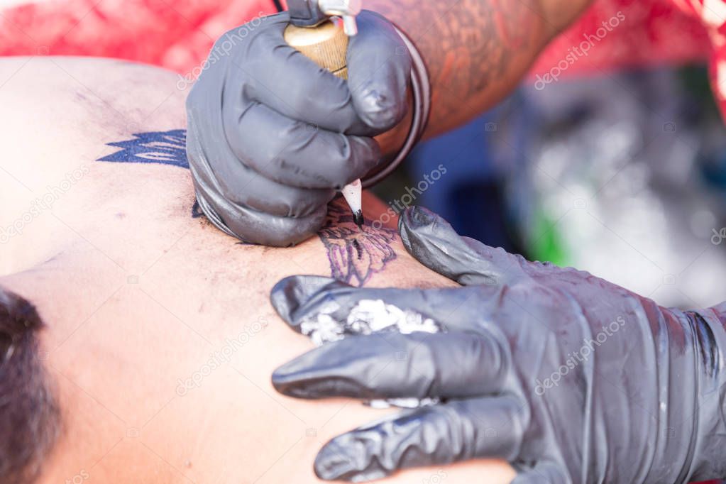 Closeup of permanent tattoo grafting drawing onto body using tools and equipment