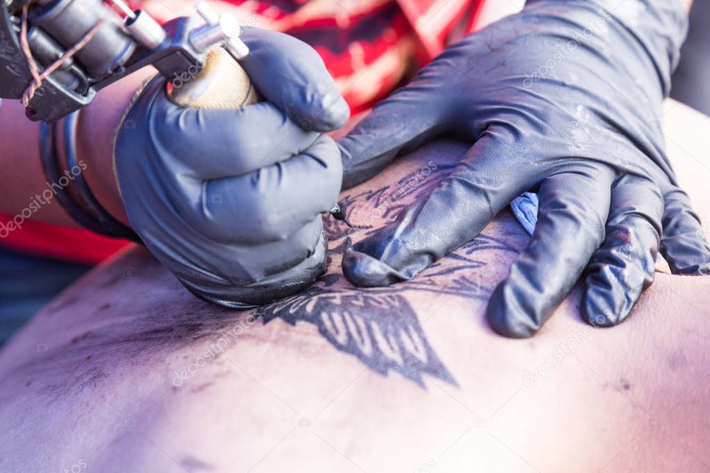 Closeup of tattoo grafting drawing onto body using tools and equipment