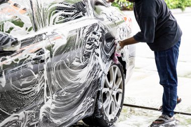 İşçi temiz araba garajında bezle deterjan sabun köpüğü kullanarak silme