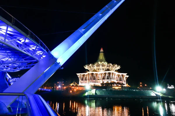 KUCHING, MALASIA, 18 de abril de 2019: El puente Darul Hana sobre el río Sarawak que supervisa el edificio de la Asamblea Estatal de Sarawak es un popular destino turístico en Kuching . — Foto de Stock