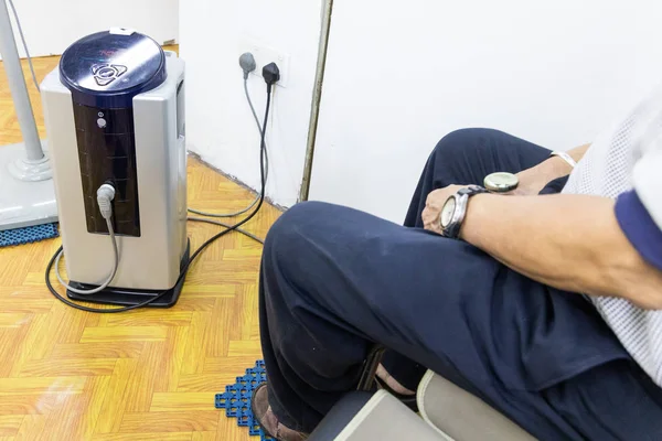 Paciente que recibe terapia electrónica de alto voltaje sentado en una hoja de aislamiento conectada al dispositivo — Foto de Stock