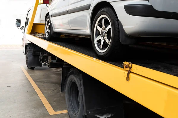 Broken car on flatbed tow truck being transported for repair — Stock Photo, Image