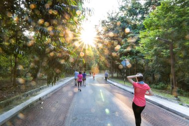 İnsanlar sabah güneş parlaklık lens parlama ile parkta yürüyüş 