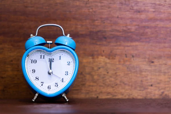 Heart shaped alarm clock on wooden background. Twelth O Clock