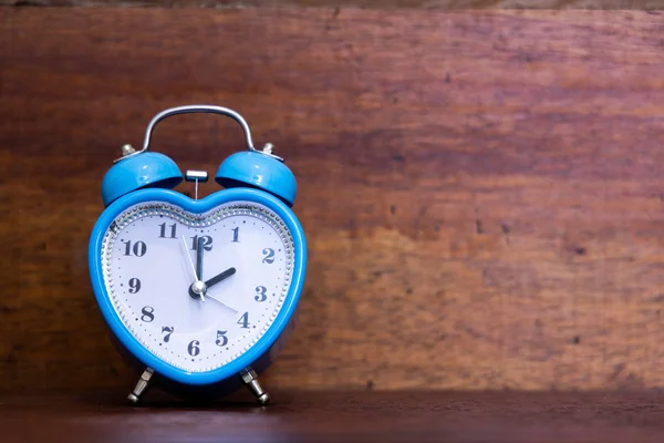 Heart shaped alarm clock on wooden background. Two O Clock