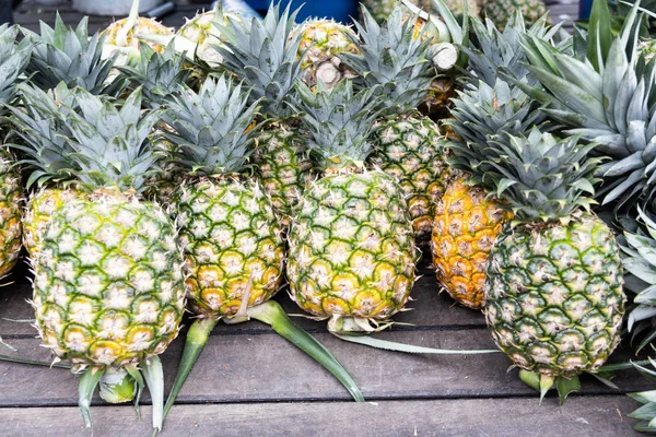 Hromádka čerstvě sklizeného organického ananasu na dřevěném povrchu — Stock fotografie