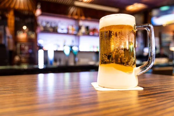 Pint of very cold and refreshing beer with pub background — Stock Photo, Image