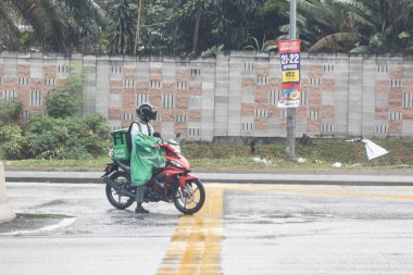 Kuala Lumpur, Malezya, 17 Eylül 2019: Grabfood, yağmurlu günlerde binici tarafından motosikletle teslim edilmesini emretti. Grabfood Asya'da en hızlı büyüyen gıda dağıtım hizmetidir.