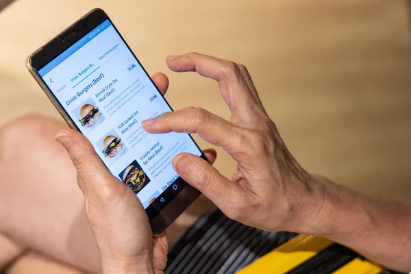 Person ordering food online via app on smart phone. Online food order and delivery is fast growing in Asia. — Stock Photo, Image