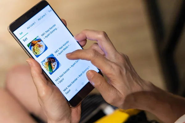 Seseorang memesan makanan secara online melalui aplikasi di telepon pintar. Pesanan dan pengiriman makanan online berkembang pesat di Asia. . — Stok Foto