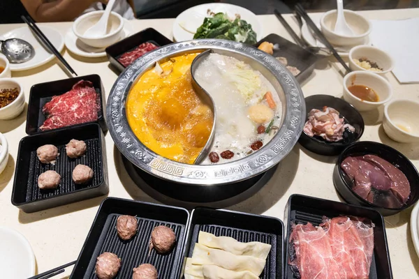 Chinesisches Dampfboot mit zwei verschiedenen Suppen mit verschiedenen Zutaten, Fleisch und Gemüse — Stockfoto