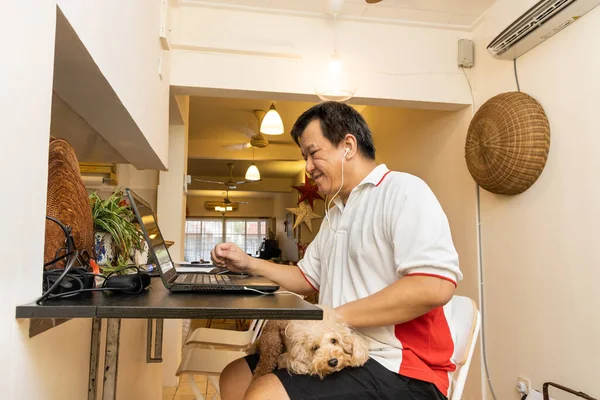 Matured Asian business man work from home accompanied by pet dog during lockdown in Malaysia